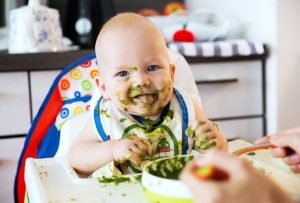 Baby bekleckert mit Babybrei