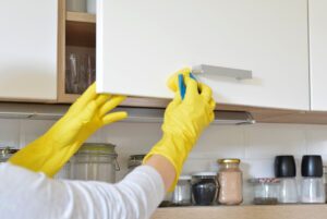 Frau reinigt Küchenschrank.