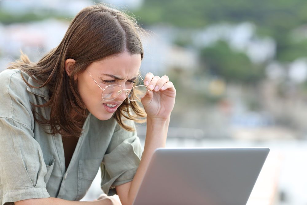 Kurzsichtige Frau kann Schrift am Computer nicht erkennen.