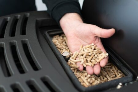 Manuelles Nachfüllen der Holzpellets beim Pelletofen.