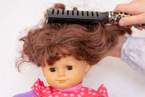 Puppe bekommt die Haare gekämmt