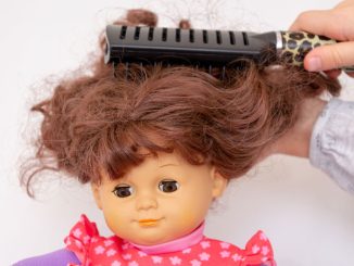 Puppe bekommt die Haare gekämmt