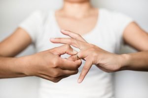 Frau versucht Ring vom Finger zu ziehen