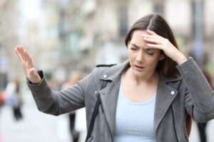 Erste Hilfe bei einem Schwindelanfall: Ursachen & Tipps Frau mit Schwindel auf der Straße.