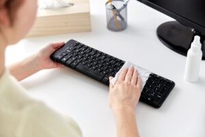 Frau reinigt Computertastatur.