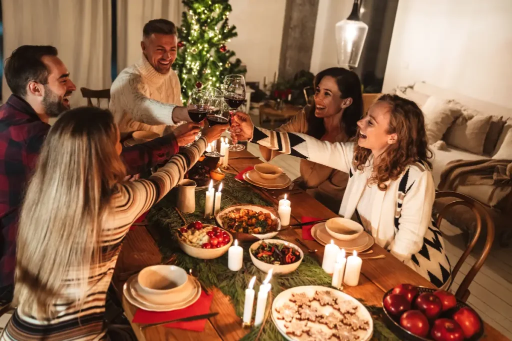Junge Leute stoßen zu Weihnachten beim Abendessen an Stressfreie Weihnachtszeit – Meine Tipps für ein entspanntes Fest ohne Nervenchaos
